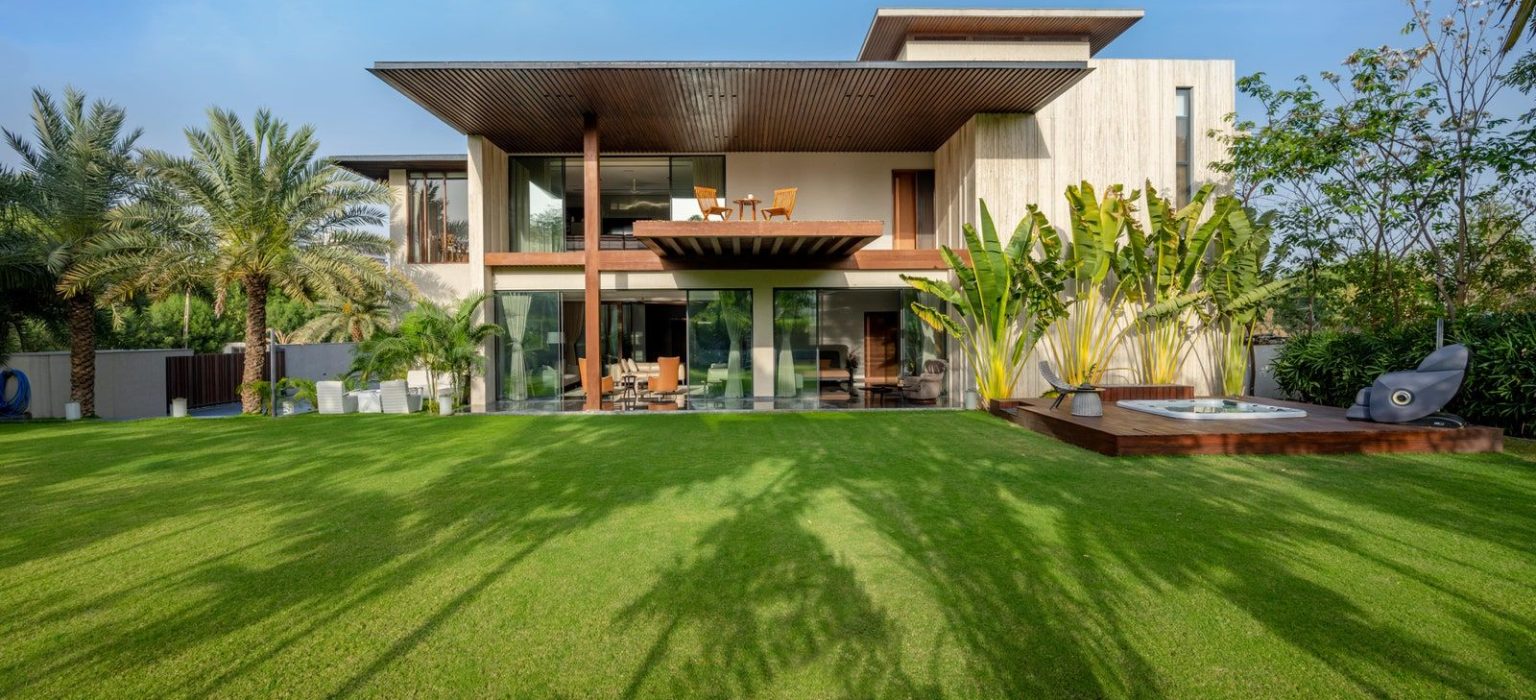 Luxury landscape design with manicured lawn, tropical plants, and wooden deck spa at modern villa by Bright Valley Landscaping